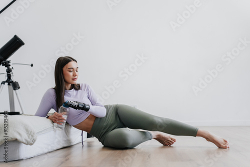 Fényképezés woman in workout attire resting on the floor with a water bottle, wearing a pros