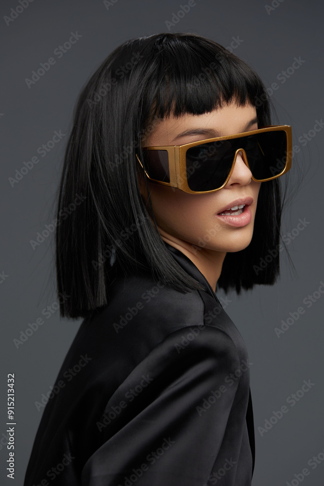 Blackhaired woman with sunglasses, in a black jacket and goldframed eyewear, looking to the side, exuding confidence and style in an urban setting Blackhaired woman with sunglasses, in a black jacket and goldframed eyewear, looking to the side, exuding confidence and style in an urban setting