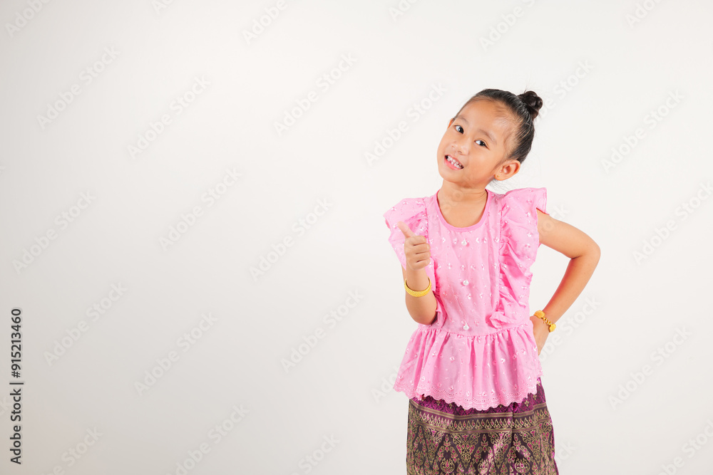 Portrait Thailand kid girl smiling traditional Thai dress costume makes thumbs up OK sign, symbolizing agreement, studio isolated white background, kindergarten child radiates positivity Portrait Thailand kid girl smiling traditional Thai dress costume makes thumbs up OK sign, symbolizing agreement, studio isolated white background, kindergarten child radiates positivity
