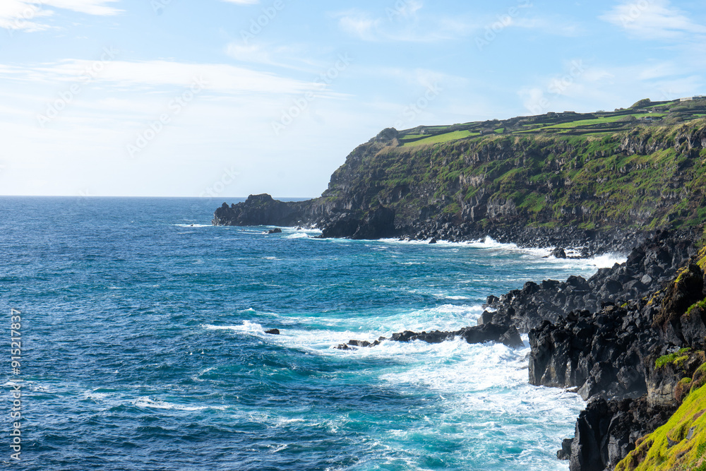 Atlantic Ocean waves crashing against volcanic rocks on the rugged coastline of Terceira Island, Azores, Portugal.