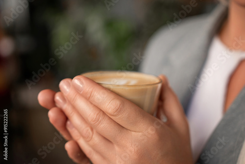 A woman is holding a cup of coffee and smiling. Concept of warmth and relaxation, as the woman enjoys her beverage.