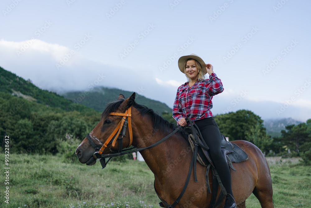 A woman is riding a horse in a field with a plaid shirt and a straw hat A woman is riding a horse in a field with a plaid shirt and a straw hat