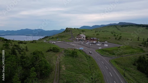 Lake Kussharo, Japan: Aerial drone footage following a car that drive throuth the top of the Bihoro Pass toward the lake Kussharo in the Akan Mahsu NP in Hokkaido in Japan in summer.  photo