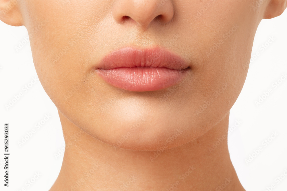 Obraz premium Lip filler injections and augmentation. Young woman with perfect lips with hyaluronic acid over white background, cropped, closeup