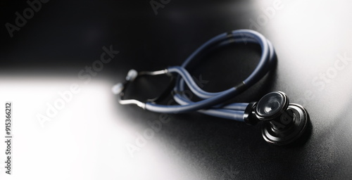 Black medical stethoscope on a dark matte background, close-up. Design element,texture. Therapist's medical tool