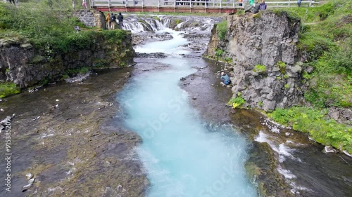 Bruarfoss waterfall flowing with tourist visiting on the bridge in wilderness during summer at Iceland photo