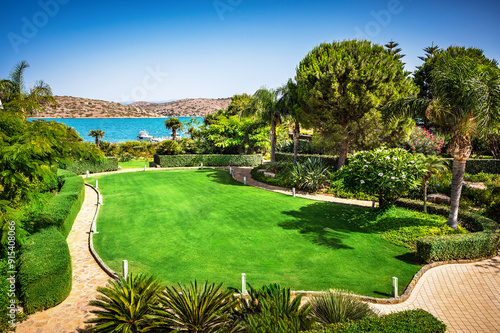 Serene Mediterranean seaside garden with lush, vibrant greenery. Foliage is rich and dense, with the deep green of the leaves contrasting beautifully against the bright. Mediterranean shimmer  photo