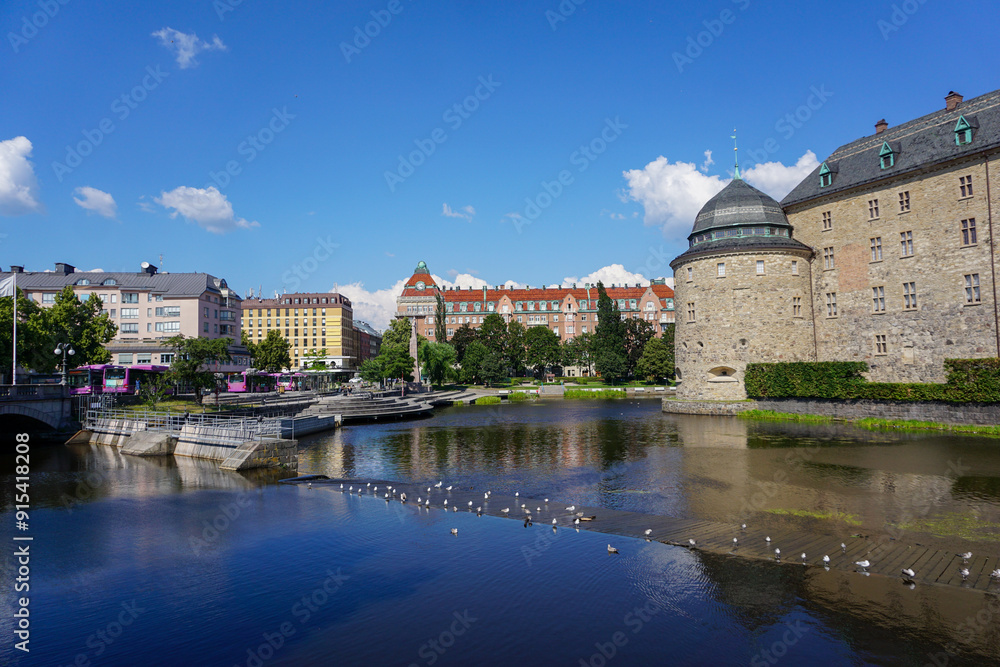 Fototapeta premium View of buildings by river against blue sky in Örebro