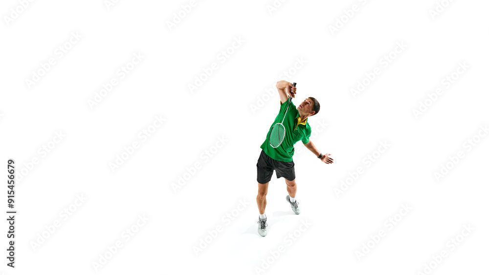 Strength and focus. Full-length image of contracted young man, badminton playing hitting shuttlecock with racket, playing isolated on white background. Concept of sport, competition, active lifestyle Strength and focus. Full-length image of contracted young man, badminton playing hitting shuttlecock with racket, playing isolated on white background. Concept of sport, competition, active lifestyle