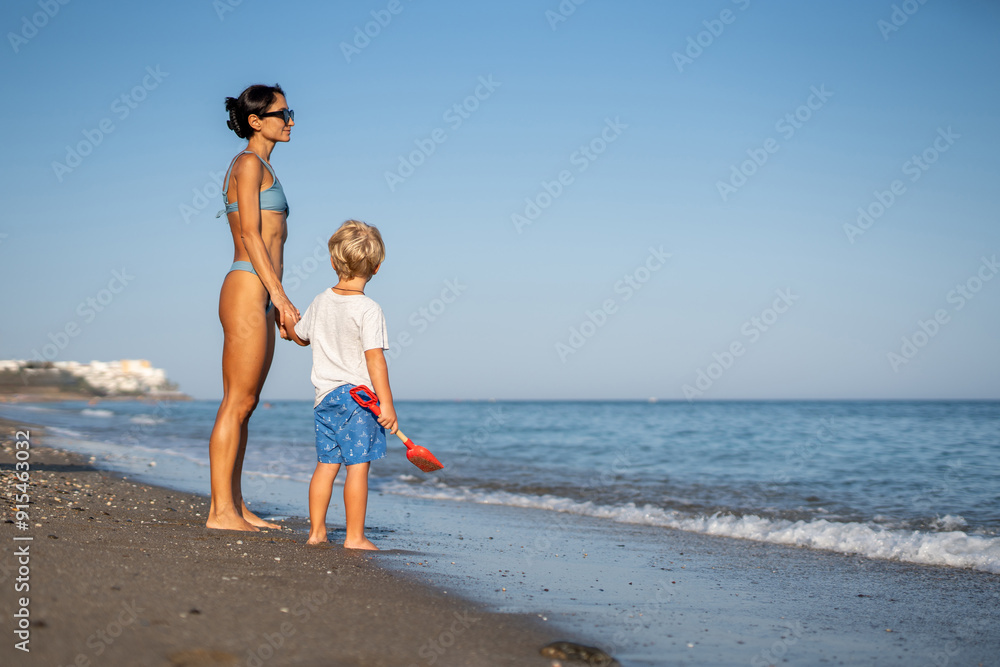 Mother and Child Gazing at the Sea on a Serene Beach Mother and Child Gazing at the Sea on a Serene Beach