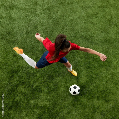 Top view photo of young sporty woman, football athlete preparing to kick ball in motion on green grass, stadium. Tournament. Concept of women and sport, team games, movement, victory, action. Ad photo