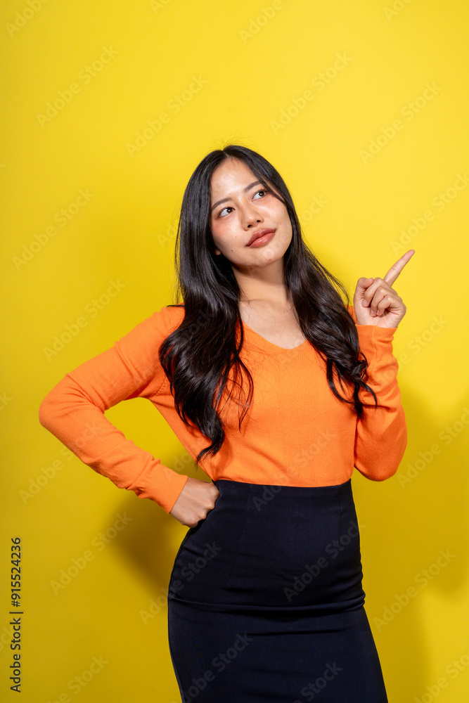 A woman in an orange shirt and black skirt is pointing to the sky A woman in an orange shirt and black skirt is pointing to the sky