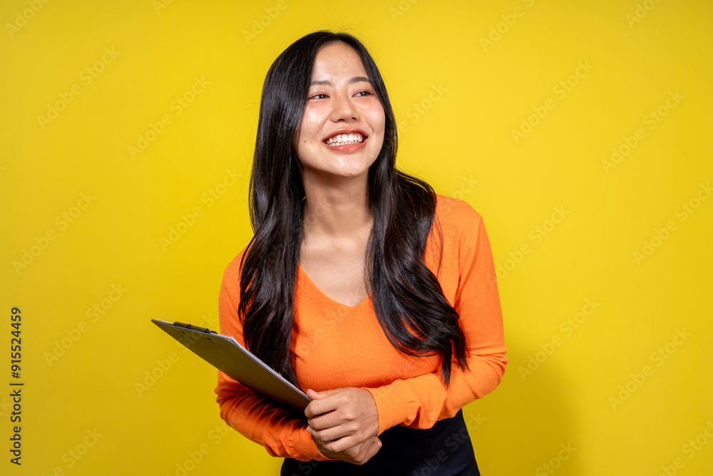 A woman in an orange shirt is holding a clipboard and smiling A woman in an orange shirt is holding a clipboard and smiling