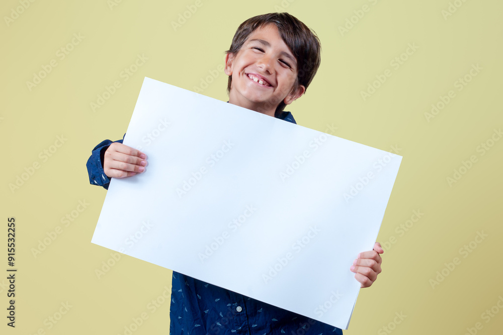 Smiling kid showing white blank banner blank for product and business advertising isolated on yellow background.