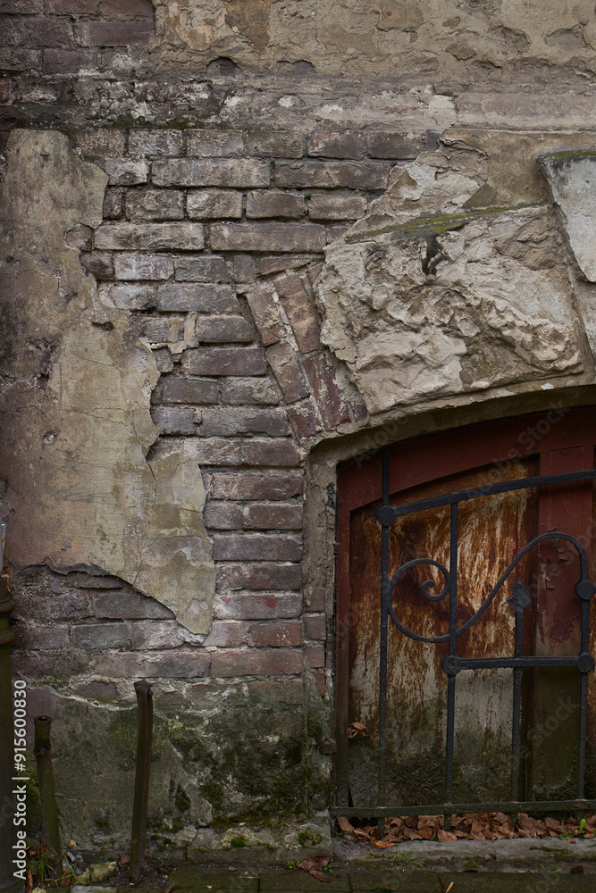 An old weathered brick wall with a rusted wooden door in a decaying building An old weathered brick wall with a rusted wooden door in a decaying building