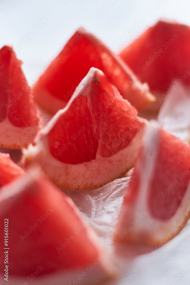 Freshly cut grapefruit segments arranged on a plate with natural light illuminating the textures Freshly cut grapefruit segments arranged on a plate with natural light illuminating the textures