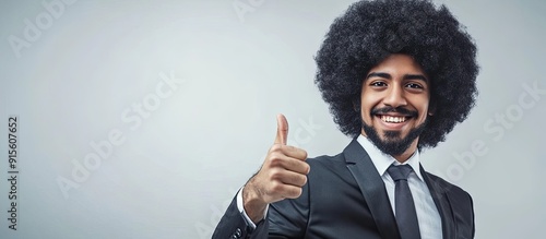 Funky businessman with a black curly afro wig is giving a thumbs up while pointing to the grey copy space on the right The smiling individual is suggesting or endorsing something positive Advertisemen photo