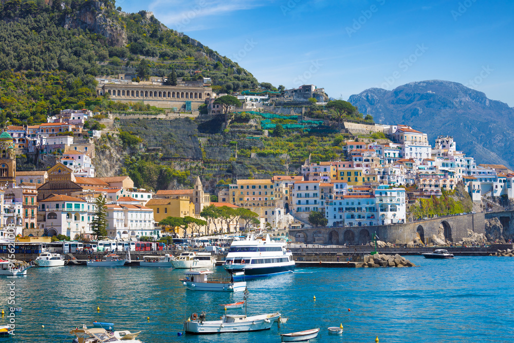 Fototapeta premium Picturesque view of Amalfi, Italy, with colorful houses, blue waters of Mediterranean Sea and ripe lemons in foreground. Amalfi coast is most popular travel and holiday destination in Europe