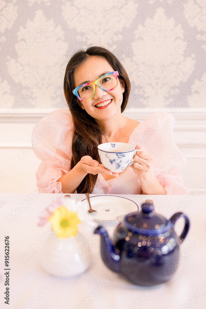 A woman wearing a pink dress enjoying English afternoon tea A woman wearing a pink dress enjoying English afternoon tea