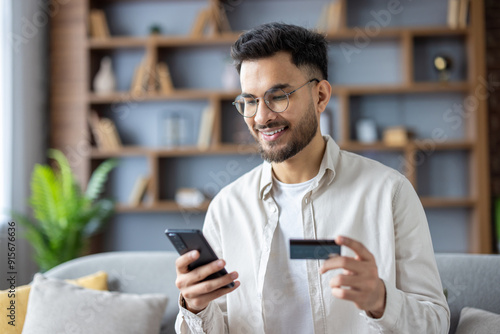 Canvas Print Close-up photo of a young Indian man sitting at home looking at the phone screen