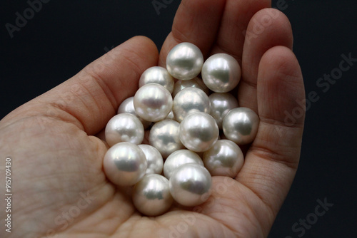 Expensive and luxurious round saltwater South Sea pearls held in the hand of a jeweler, ready to be made into earrings, pendants or necklaces and sold in jewelry store. Popular wedding accessory. photo