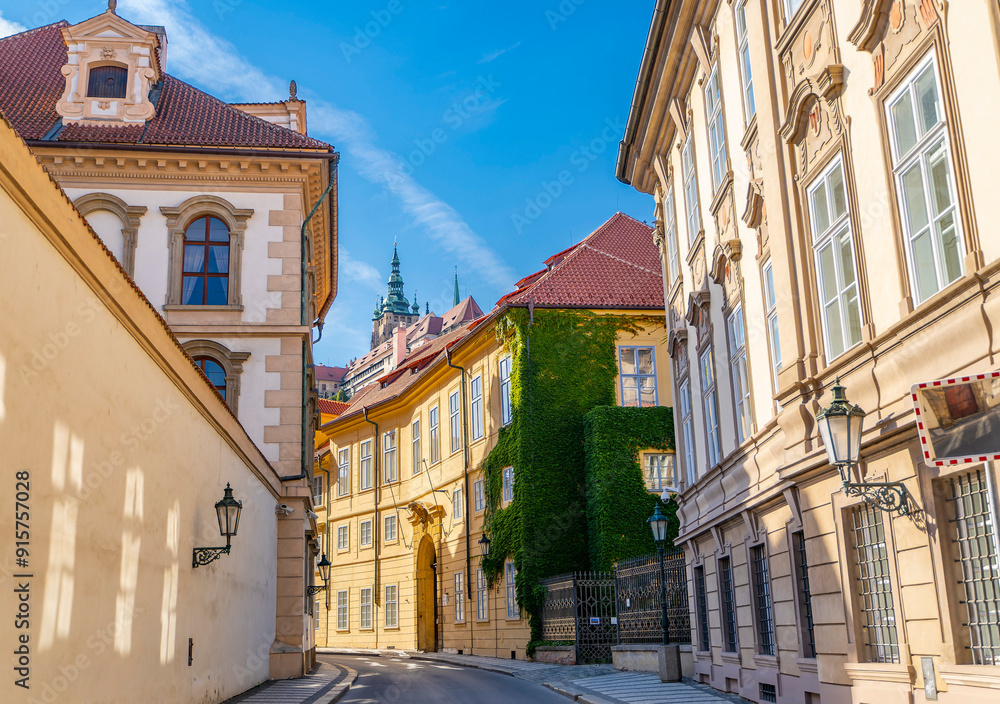Naklejka premium Narrow street with old buildings in Prague, Czech Republic, green ivy plants growing on wall.