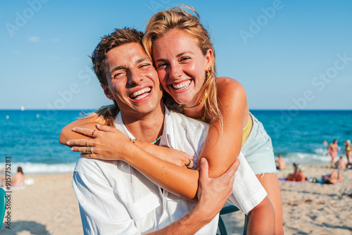 Konstfotografi Close up portrait of a young Caucasian tourist couple hugging and looking at the camera on the beach while enjoying their summer vacation on the coast