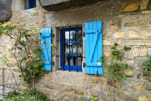 Les chaumières de Kérascoët en été, avec leurs toits de chaume et leurs fenêtres à petits carreaux entourées de volets bleus et de rosiers, dégagent une atmosphère romantique et bucolique. photo