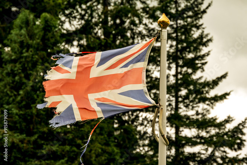 union jack flag: faded, worn, shredded, and torn blowing horizonal in strong wind from right to left photo