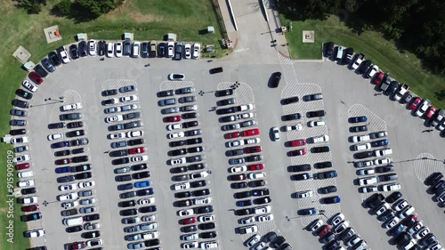 Entrance to large parking lot full of electric, gas vehicles and cars driving around looking for available spot, people walking, parallel pattern, pavement marking number in metropolitan, flyover. USA