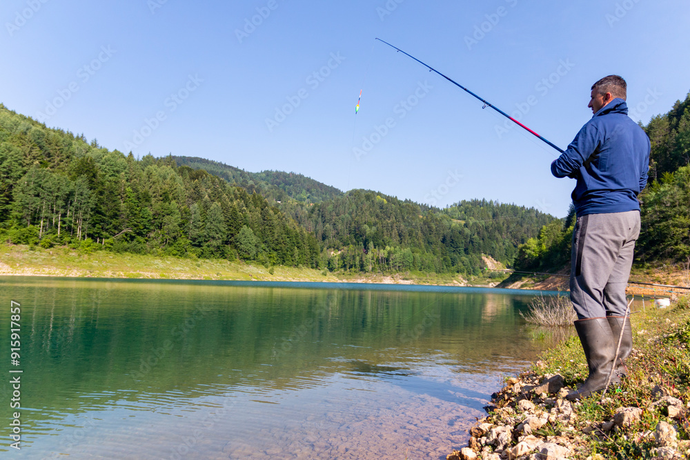 A young fisherman on the river catching a fish with his fishing rod A young fisherman on the river catching a fish with his fishing rod