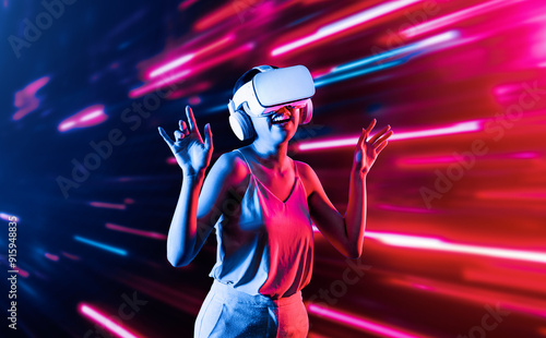 Smart female standing surrounded by neon light wearing VR headset connecting metaverse, future cyberspace community technology. Elegant woman enjoy dancing wavering body and sing song. Hallucination.