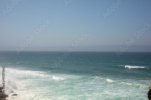 The ocean stretches out endlessly waves crashing against the shore The sky is a perfect blue photo