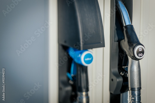 A close up image of fuel nozzles at a gas station, featuring options for 95E, 98E, and DD Diesel. The nozzles are neatly placed in their holders, showcasing the stations fuel variety.