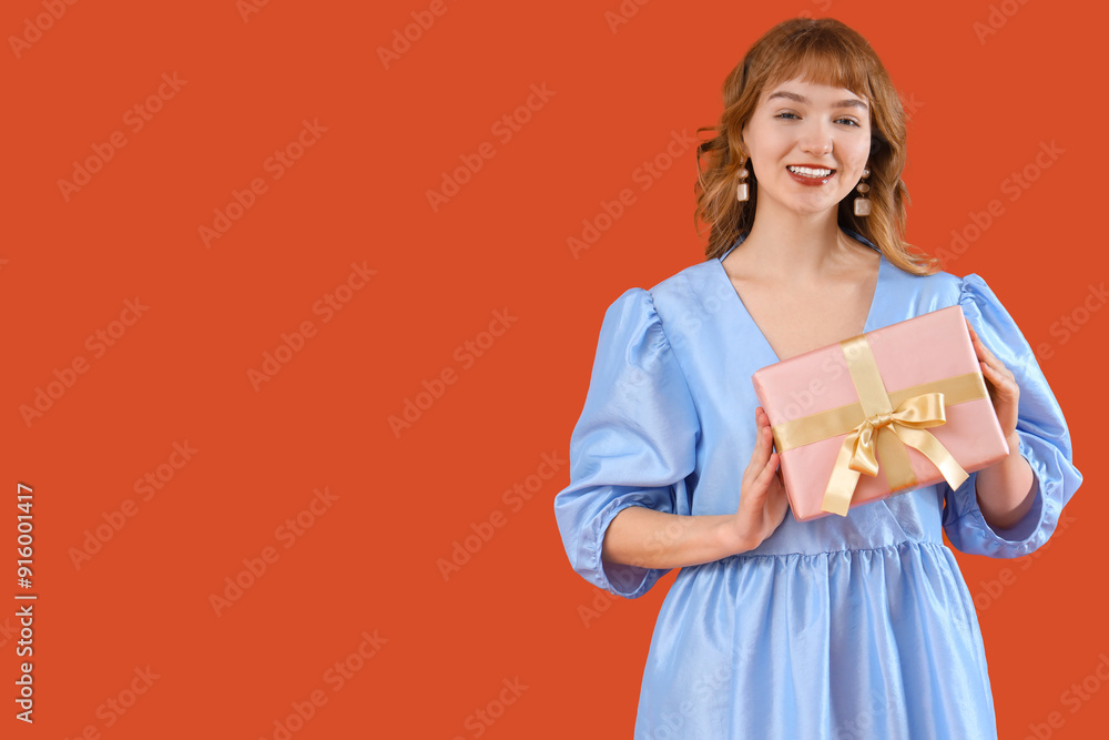 Beautiful young woman with gift box on orange background Beautiful young woman with gift box on orange background