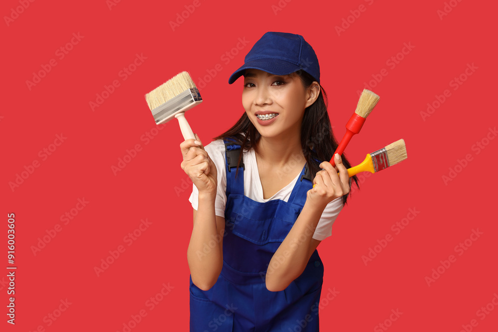 Female Asian happy painter with brushes on red background Female Asian happy painter with brushes on red background