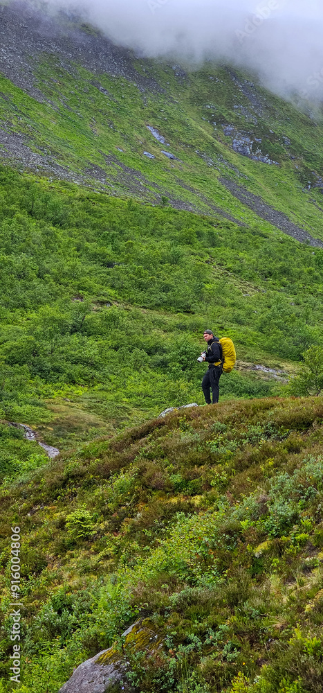 Fototapeta premium male hiker in the fjord of Andalsnes - Isfjorden in Norway hiking on a rainy cloudy day in the mountains of Massvassbu