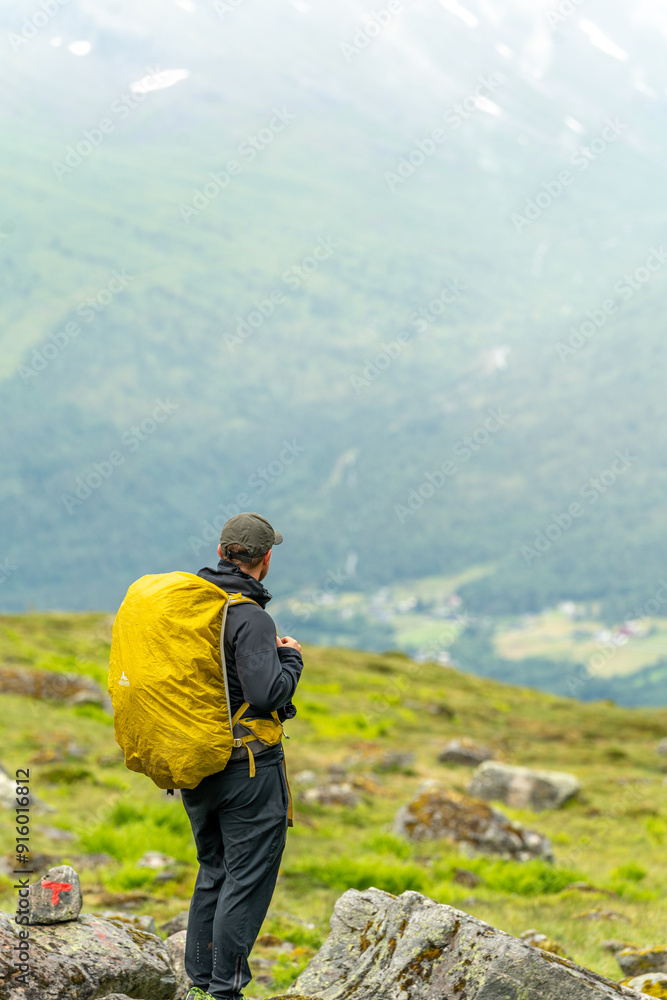 male hiker in the fjord of Andalsnes - Isfjorden in Norway hiking on a rainy cloudy day in the mountains of Massvassbu male hiker in the fjord of Andalsnes - Isfjorden in Norway hiking on a rainy cloudy day in the mountains of Massvassbu