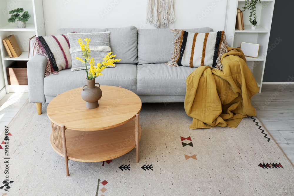 Obraz premium Interior of living room with sofa, table and artificial flowers in vase