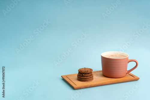The chocolate chip cookie biscuit with a cup of chocolate drink on a blue background. 