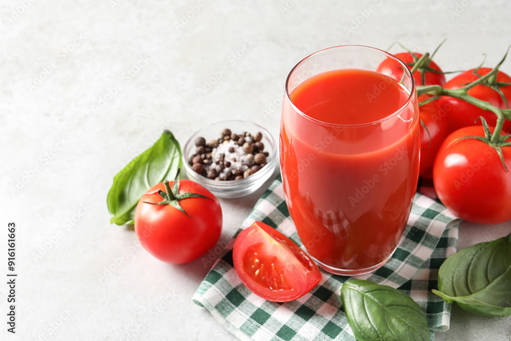 Tasty tomato juice in glass, spices and fresh vegetables on light table, space for text Tasty tomato juice in glass, spices and fresh vegetables on light table, space for text