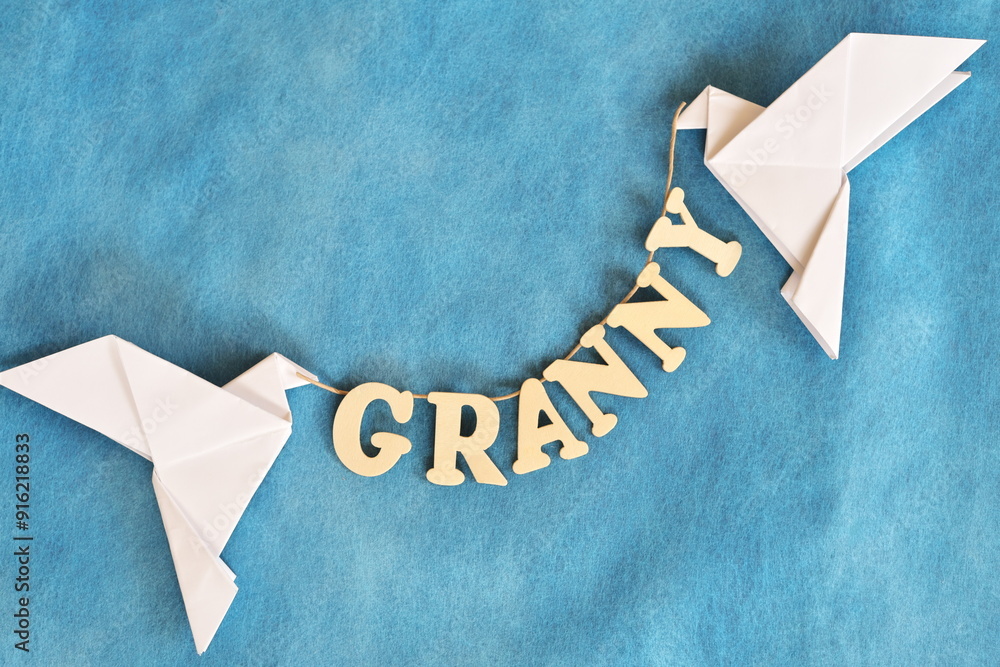 Grandparents in heaven concept. Two white dove carrying word granny in sky blue background.