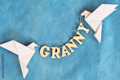 Grandparents in heaven concept. Two white dove carrying word granny in sky blue background.