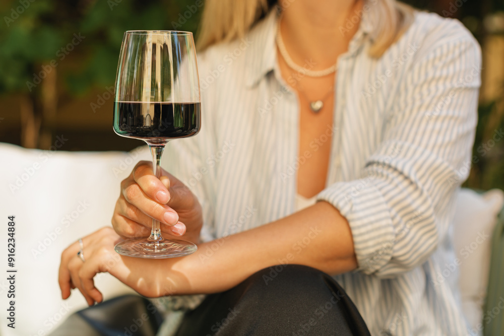 Close-up of a woman Enjoying a glass of red wine while sitting on a summer terrace Close-up of a woman Enjoying a glass of red wine while sitting on a summer terrace