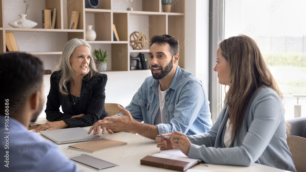Confident handsome Latin manager man in casual talking to business partners, diverse colleagues at office large table, interviewing job candidate, smiling. Team meeting for communication. Banner shot Confident handsome Latin manager man in casual talking to business partners, diverse colleagues at office large table, interviewing job candidate, smiling. Team meeting for communication. Banner shot