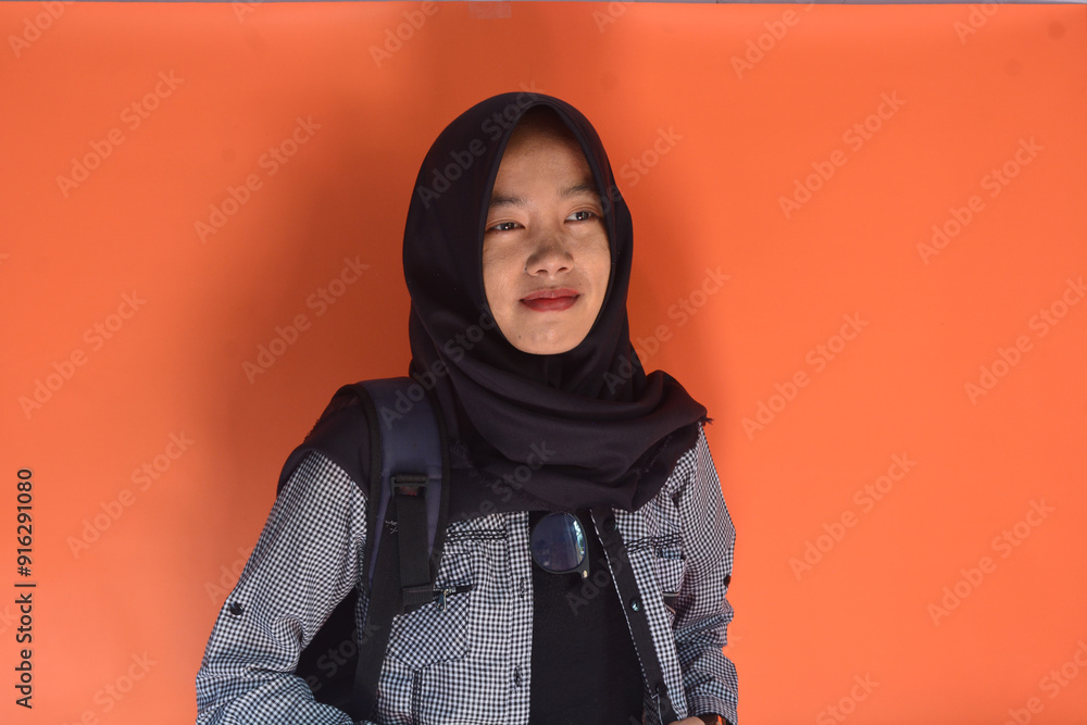 Portrait of an Indonesian schoolgirl wearing a bag on her back and carrying a book in her hand Portrait of an Indonesian schoolgirl wearing a bag on her back and carrying a book in her hand