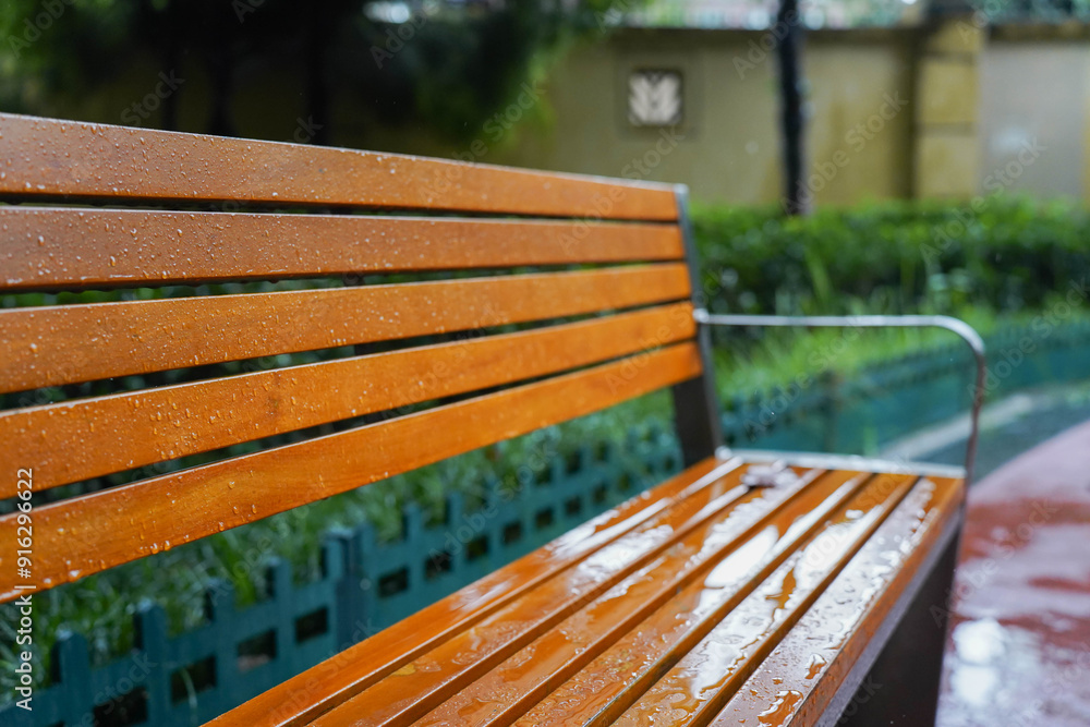 wooden bench standing on the sides of the paved paths of neighbourhood on a rainy day, Chengdu, China.