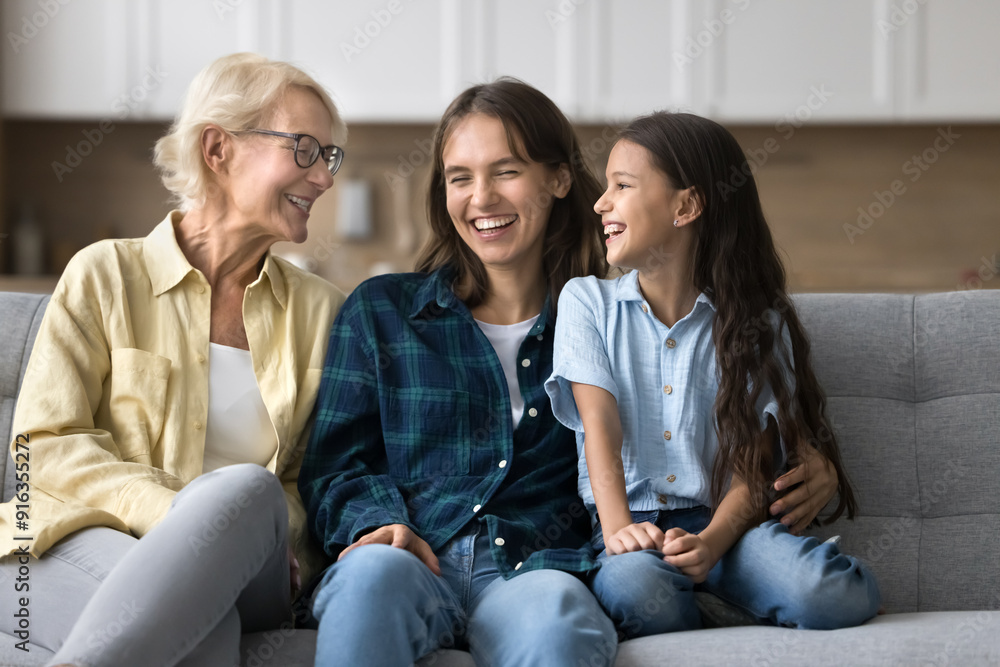 Happy child, mother and grandmother meeting at home, talking and laughing on comfortable couch, hugging with love, warmth, care, enjoying family relations, communication Happy child, mother and grandmother meeting at home, talking and laughing on comfortable couch, hugging with love, warmth, care, enjoying family relations, communication