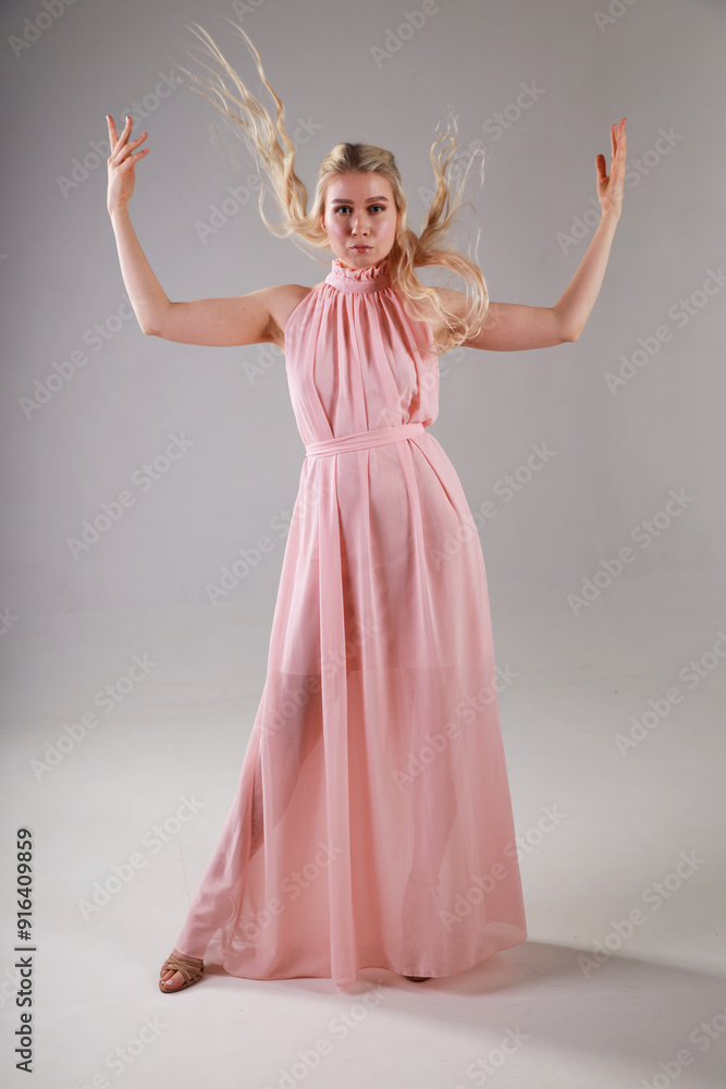 Beautiful young blonde woman in pink dress on grey background full length Beautiful young blonde woman in pink dress on grey background full length