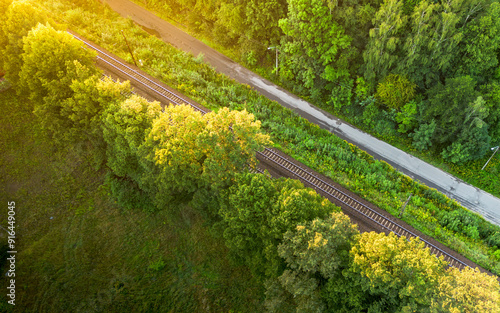 Aerial view of railway tracks bordered by lush greenery during golden hour